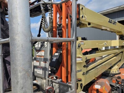 Close-up of JLG X700AJ boom lift platform and controls with sky background.