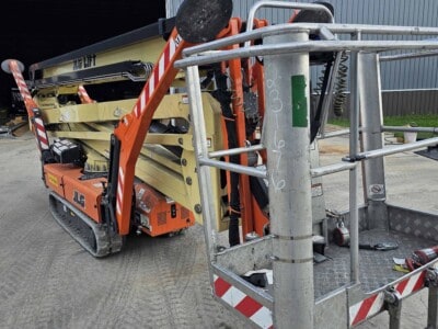 2015 JLG X700AJ boom lift with extended platform and tracks, parked outside a warehouse.
