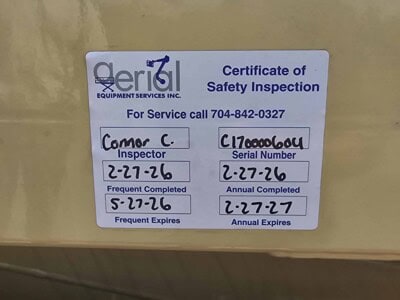 Certificate of Safety Inspection label on yellow equipment with serial number and inspection dates.