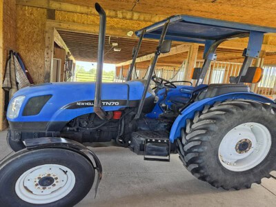 2004 New Holland TN70 blue tractor with cab and large rear tires.