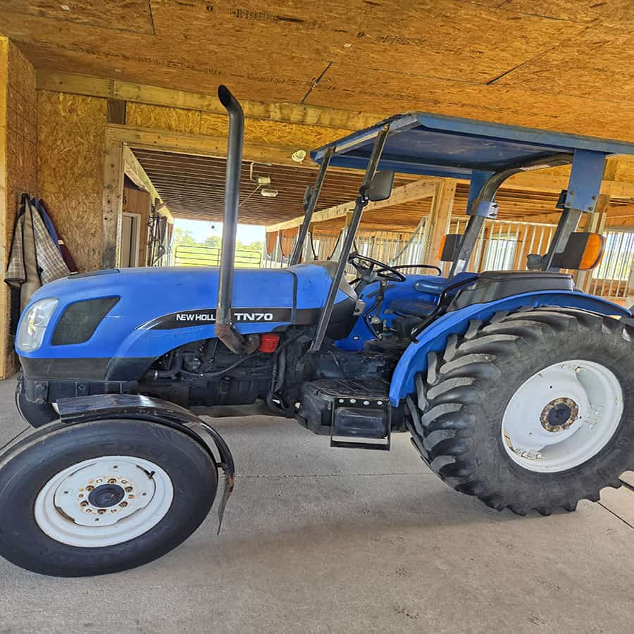 2004 New Holland TN70 blue tractor with cab and large rear tires.