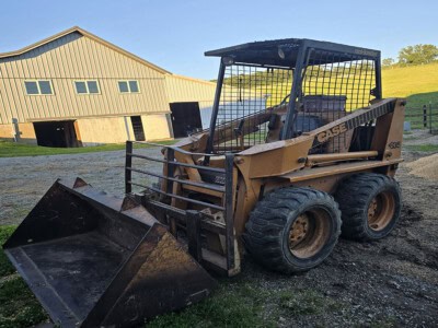 Case 1835 skid steer loader with bucket attachment on a farm.