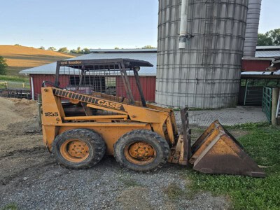 Case 1835 skid steer loader with bucket attachment on farm ground.