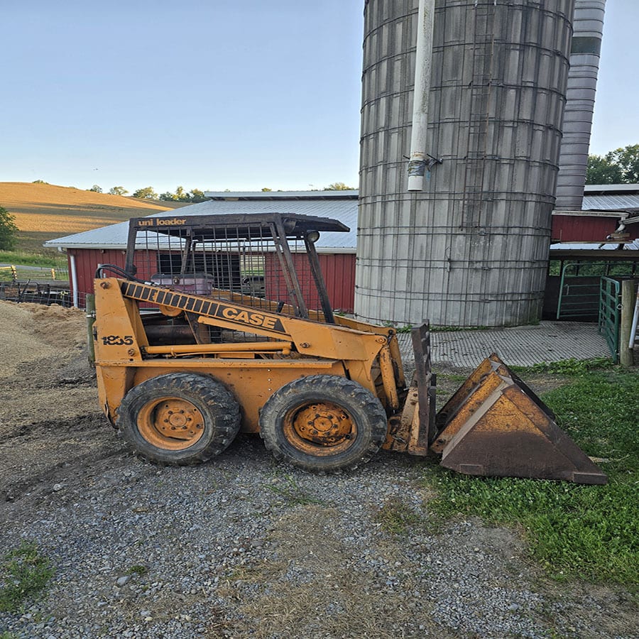 Case 1835 skid steer loader with bucket attachment on farm ground.
