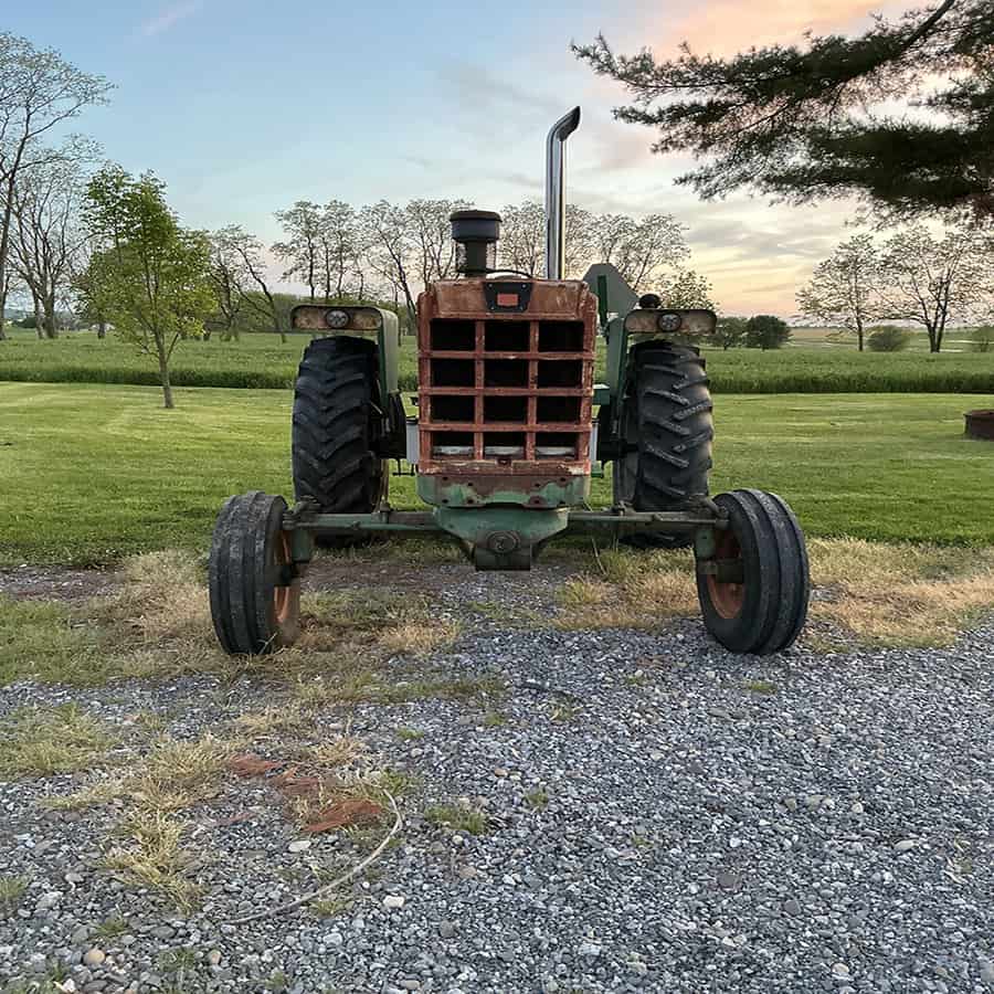 Oliver 1550 Tractor in Field Oliver 1550 vintage tractor with rusted front grille and large rear tires in a rural setting.