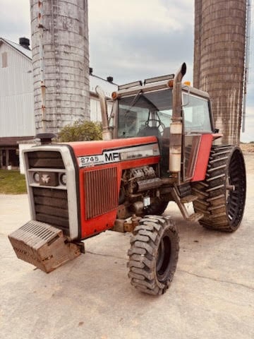 Massey Ferguson 2745 tractor with cab and large rear tires, parked near silos.