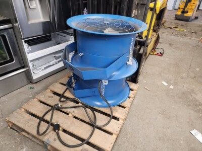 Blue industrial fan with protective guard and power cord on wooden pallet.