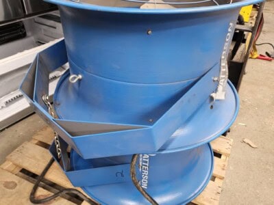 Blue industrial fan with protective guard and electrical cords, used for ventilation or cooling in industrial settings.