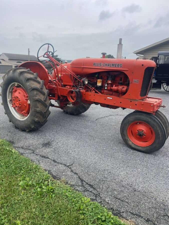 Red Allis-Chalmers WD vintage tractor with large rear tires and open cab.