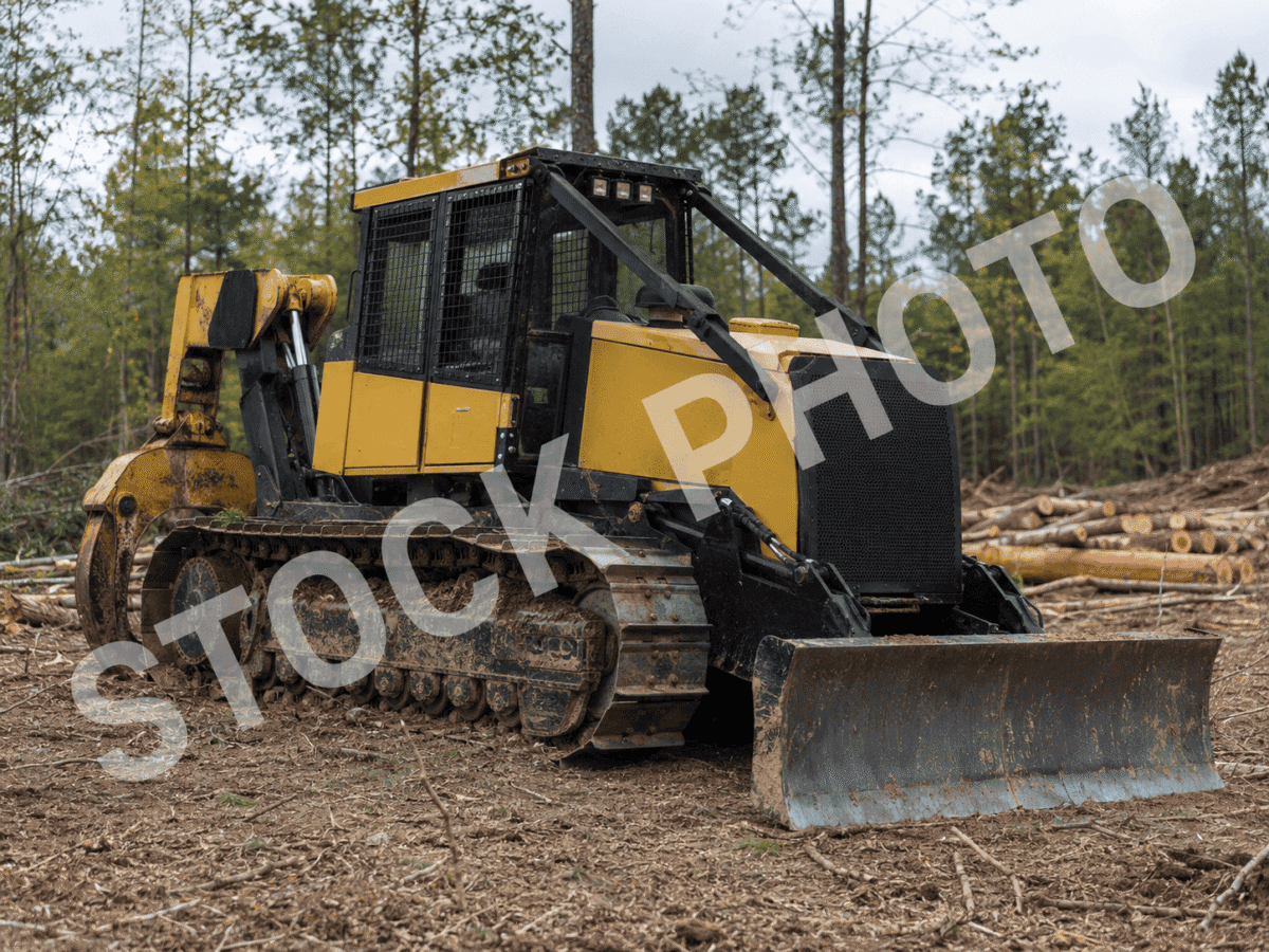 KMC 1000AG track skidder with enclosed cab and blade attachment in a forest clearing.