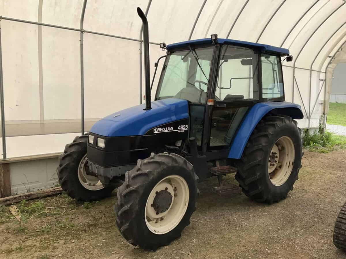 New Holland 4635 tractor with enclosed cab and large rear tires.