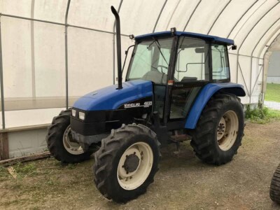 New Holland 4635 tractor with enclosed cab and large rear tires.