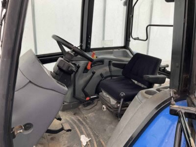 Cabin interior of a John Deere 5075E tractor with steering wheel and seat.