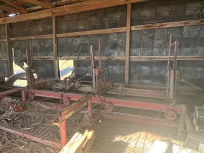 Large industrial saw mill with multiple cutting stations and conveyor system in a warehouse setting.