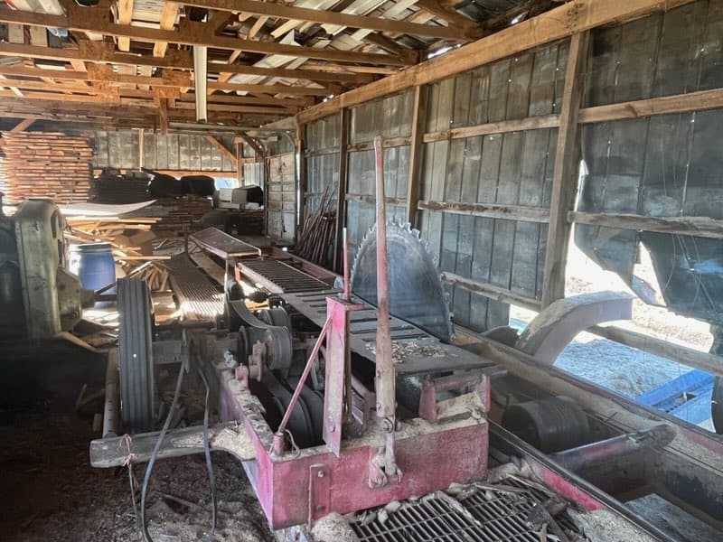 Old sawmill machinery with rust and wear in rustic barn setting.