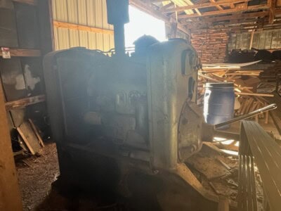 Old industrial engine with visible wear and rust in a wooden shed.