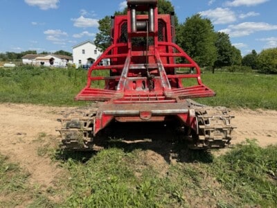KMC 1000AG track skidder with red frame and tracked wheels on grassy field.