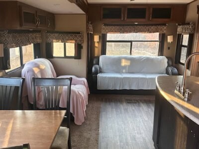 Spacious RV interior with sofa, dining area, and kitchen.
