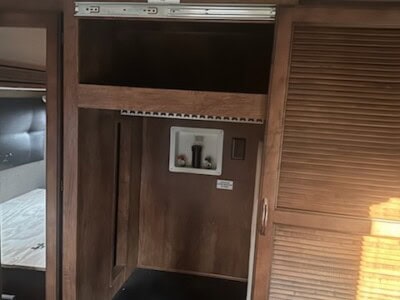 Wooden wardrobe with sliding door and built-in electrical outlet.