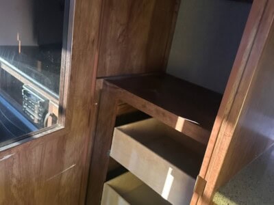 Wooden kitchen cabinet with open shelves and a glass door on the left side.