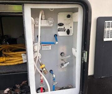 RV water hookup panel with hoses, valves, and control panel for water management.