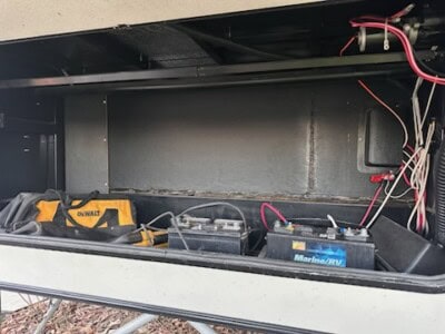 Battery and wiring compartment of equipment with tools and cables inside.