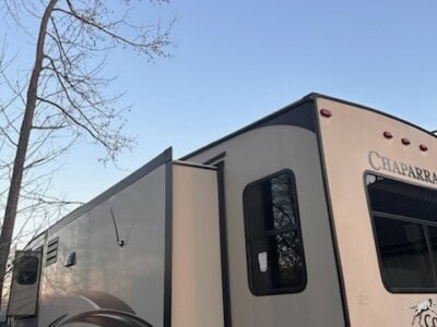 2021 Chaparral fifth wheel RV with slide-out and black accents under a clear sky.