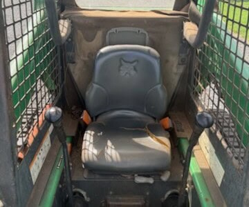 Cab interior of a 2005 BOBCAT T190 compact track loader with protective mesh sides and operator seat.