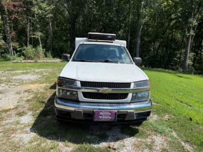 2012 Chevrolet Colorado pickup truck with extended cab and roof rack in a grassy area.
