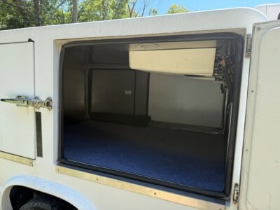 Empty cargo area of a white service utility van with open side door.
