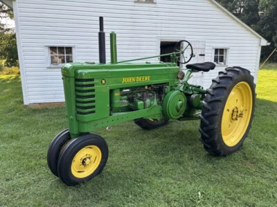 1947 John Deere B vintage tractor with green body and yellow wheels on grass.