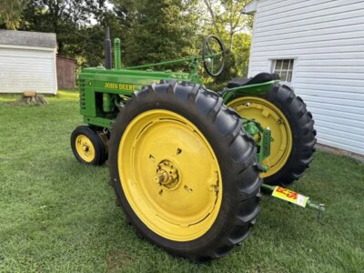 Vintage 1947 John Deere B tractor with green body and yellow wheels on grass.