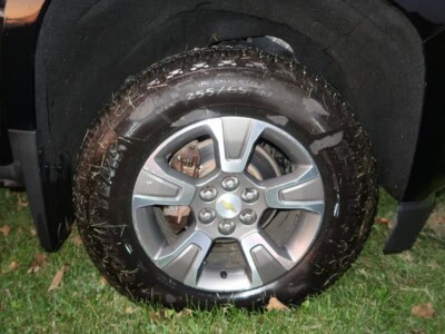 2018 Chevrolet Colorado Z71 tire and alloy wheel with mud and grass.