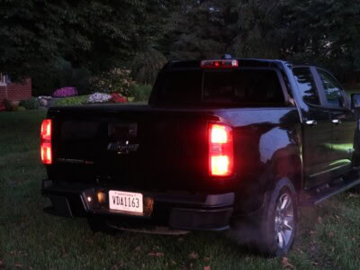 2018 Chevrolet Colorado Z71 black pickup truck with tinted windows and rear view, parked on grass at dusk.