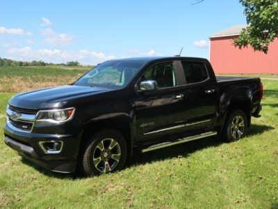2018 Chevrolet Colorado Z71 black pickup truck on grassy field with barn in background.