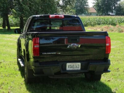 2018 Chevrolet Colorado Z71 black pickup truck in grassy field with trees.