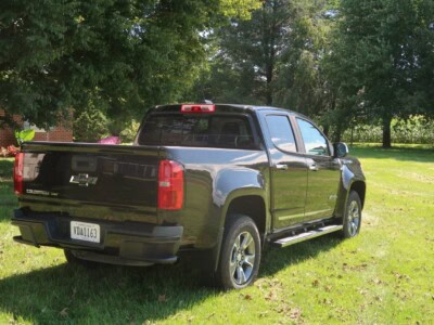 2018 Chevrolet Colorado Z71 black pickup truck parked on grass with trees in background.