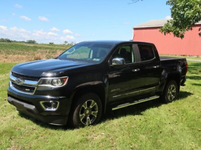 2018 Chevrolet Colorado Z71 black pickup truck on grass with barn in background.