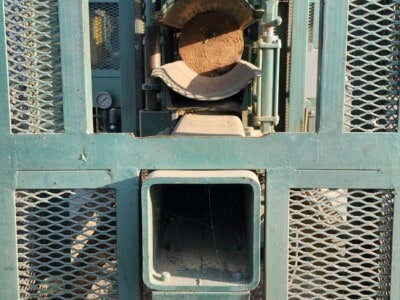 Warning sign on industrial log birsmouth machine indicating pinch point hazard.