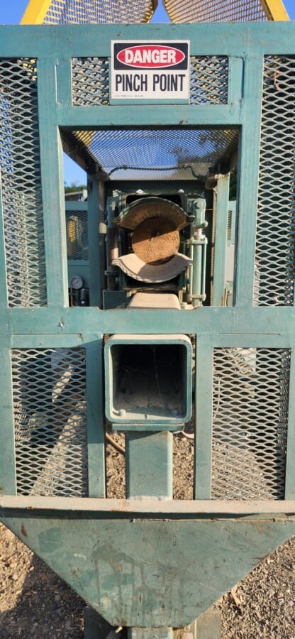 Warning sign on industrial log birsmouth machine indicating pinch point hazard.