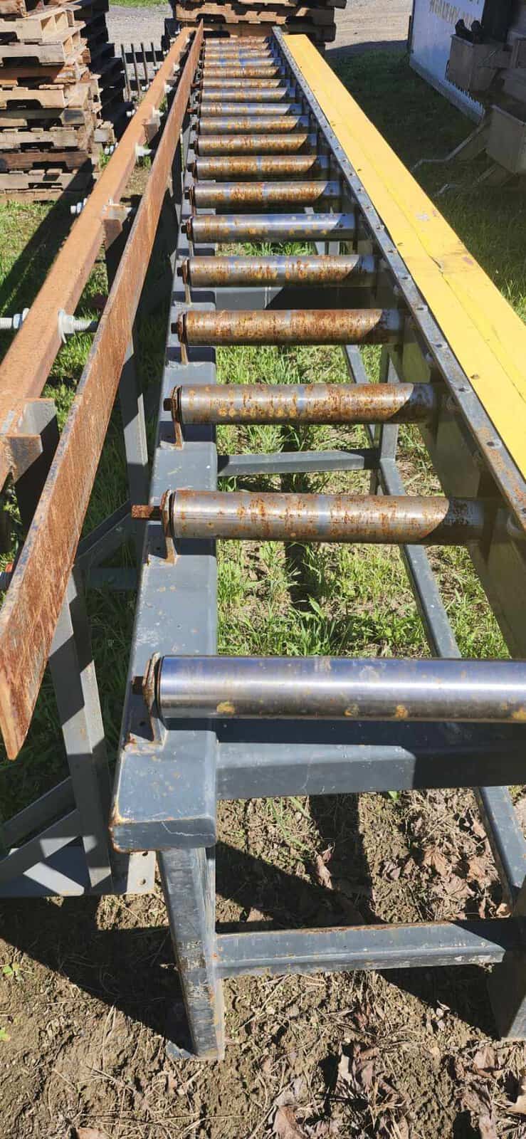 Industrial Log Birsmouth Machine Roller Conveyor Roller conveyor for log handling with rusted rollers and yellow frame.