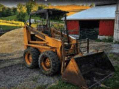 CASE 1835 skid steer loader with bucket attachment on farm gravel path.