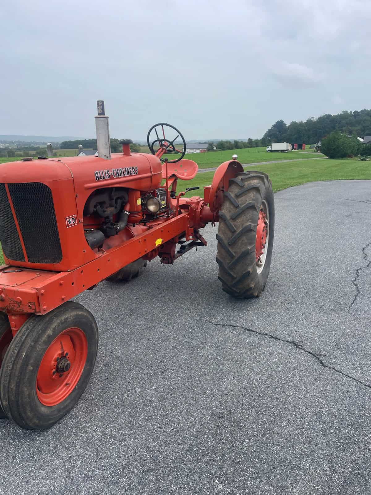 Allis-Chalmers WD Tractor for Sale Vintage Allis-Chalmers WD tractor with orange paint and large rear tires on a paved lot.