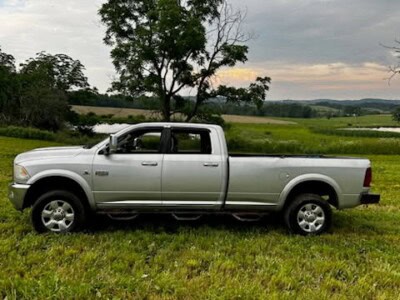 Silver 2021 Ram 2500 pickup truck with extended cab and long bed on grassy field.