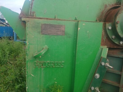 Green Progress industrial machine with visible rust and wear, outdoor setting with grass and other equipment.