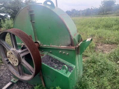 Green industrial metal cutting saw with large wheel and handle in outdoor setting.