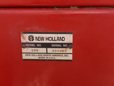 Close-up of New Holland 565 equipment serial plate with model and serial number details.
