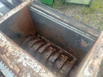 Rusty industrial shredder with metal blades and wear marks.