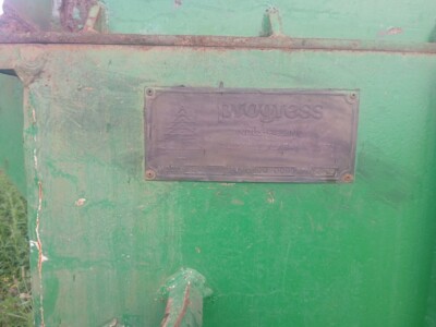 Green industrial equipment with a metal nameplate reading 'Progress' and visible wear.