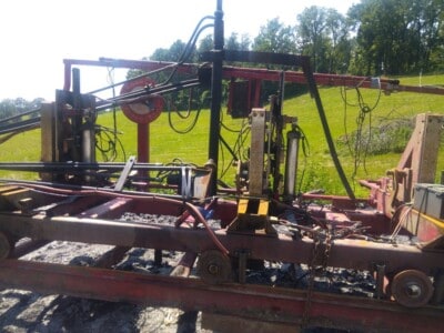 Heavy-duty industrial sawmill equipment with hydraulic components and conveyor system.
